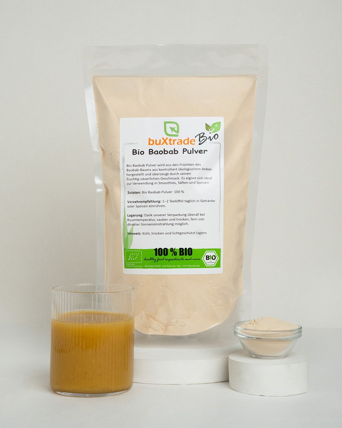 Verpackung von buXtrade Bio Baobab Pulver mit Glas Saft und Schale Pulver.