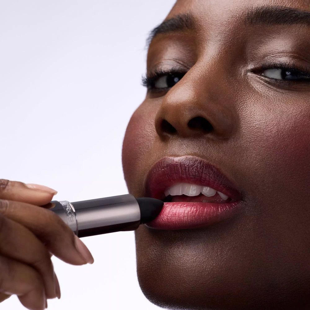 Person trägt Lippenstift auf. Die Lippen sind dunkelrot. Der Lippenstift ist silberfarben. Marke: Catrice.