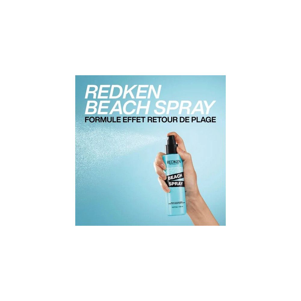 Hand hält eine blaue Sprühflasche. Text: Redken Beach Spray, Formule effet retour de plage. Sprühnebel.