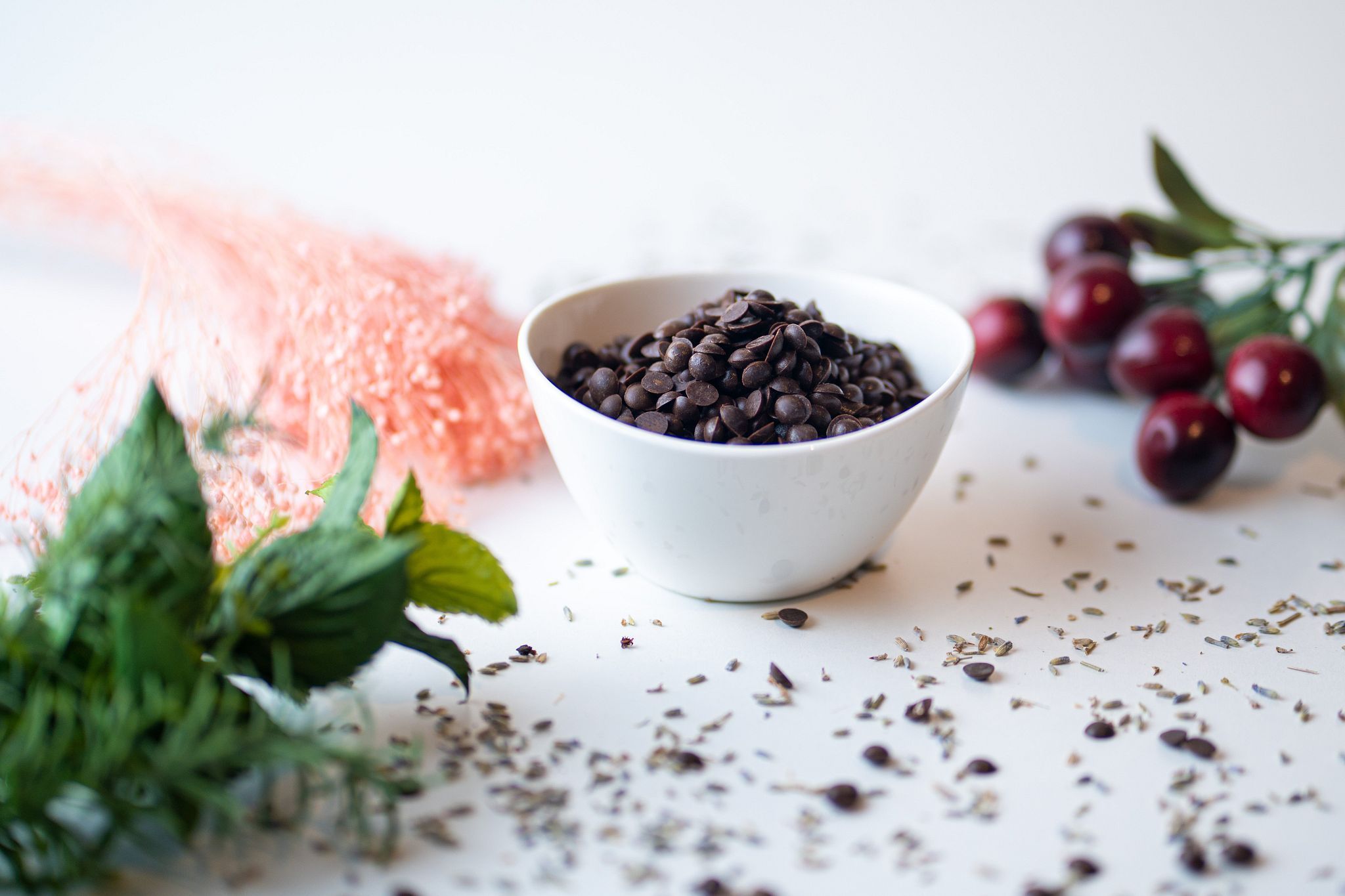 Weiße Schale mit Schokodrops. Dekoration mit Pflanzen und Beeren.