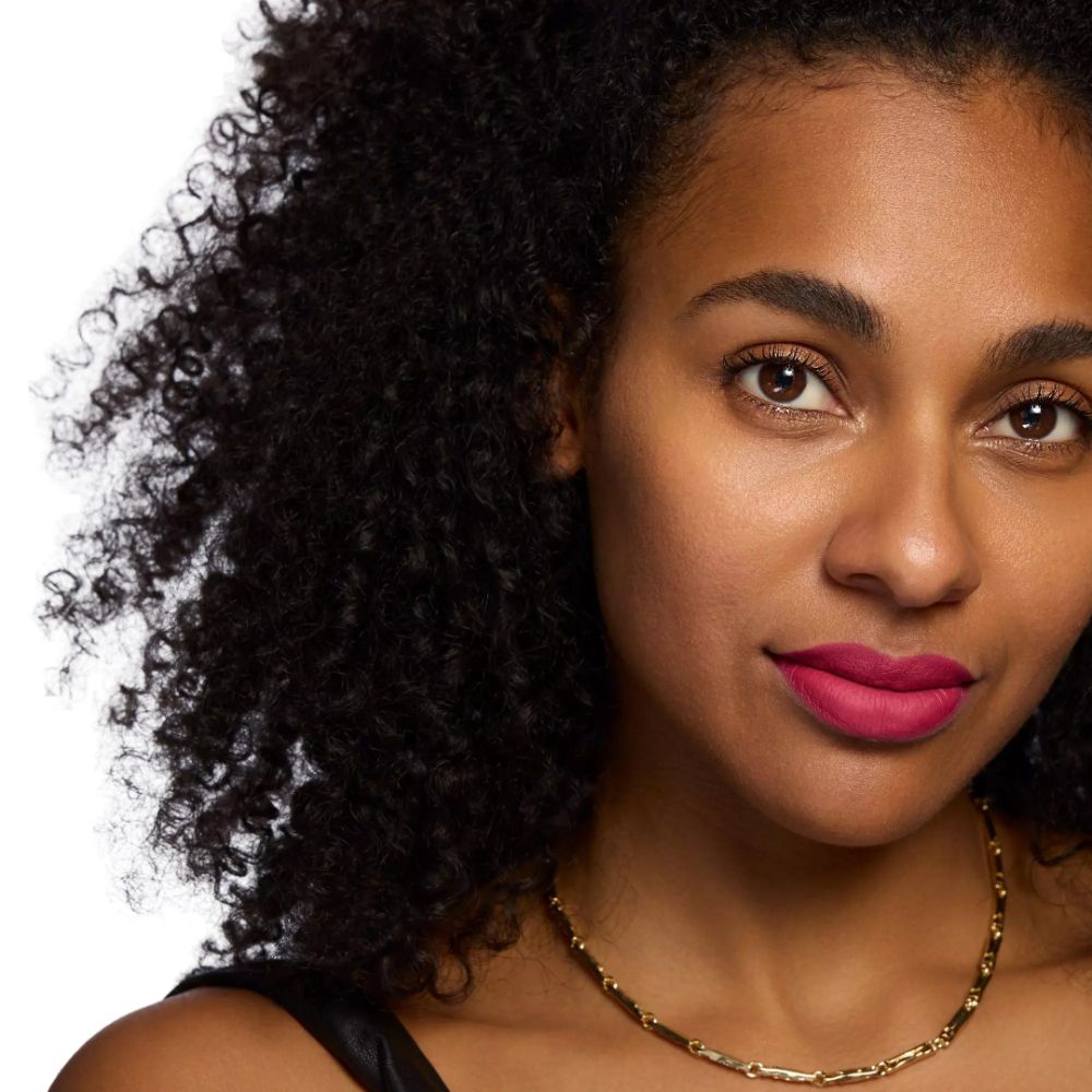 Porträt einer Frau mit lockigem Haar und rotem Lippenstift.