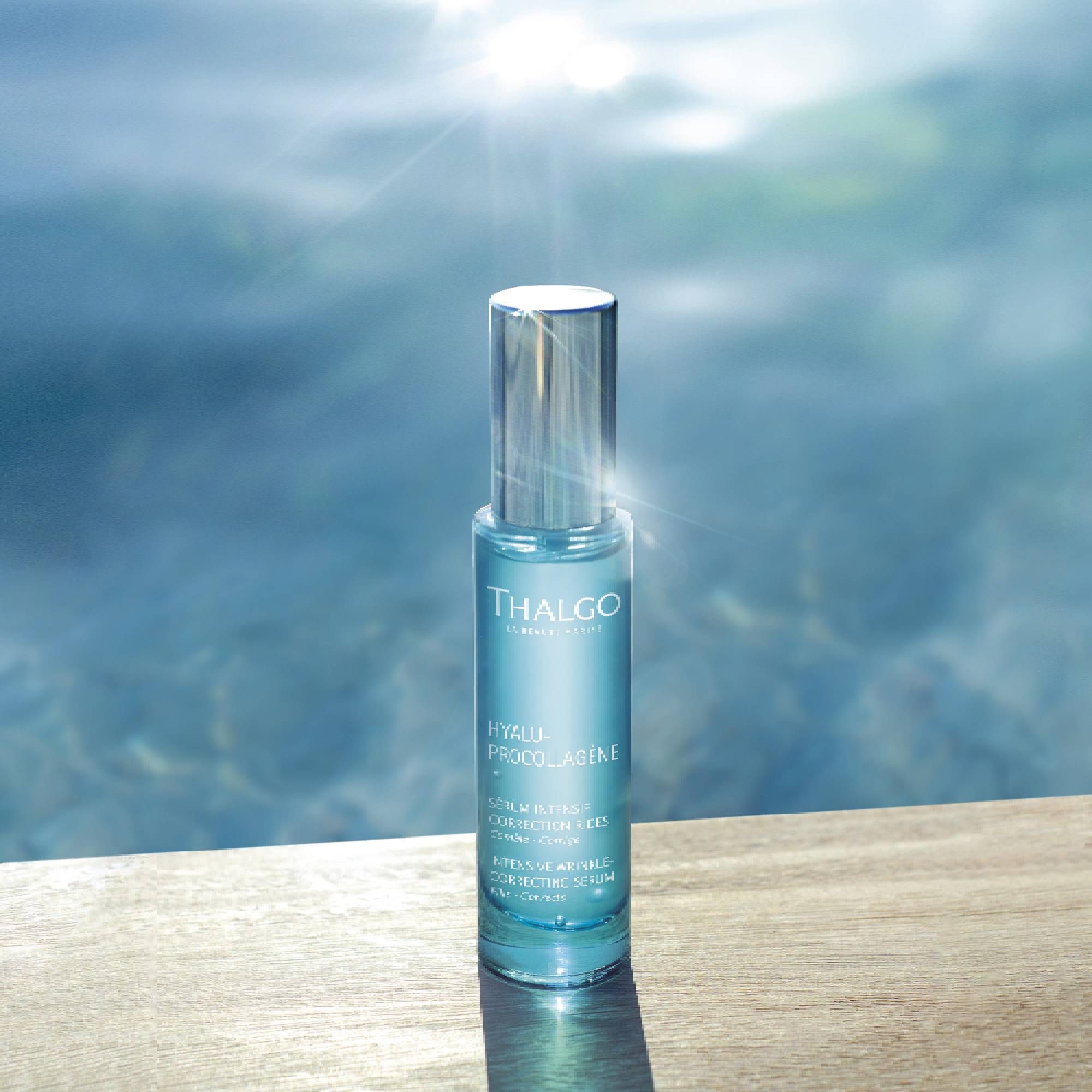 Türkisfarbene Serumflasche mit silbernem Deckel auf Holzoberfläche. Beschriftung: THALGO, HYALU-PROCOLLAGÈNE.
