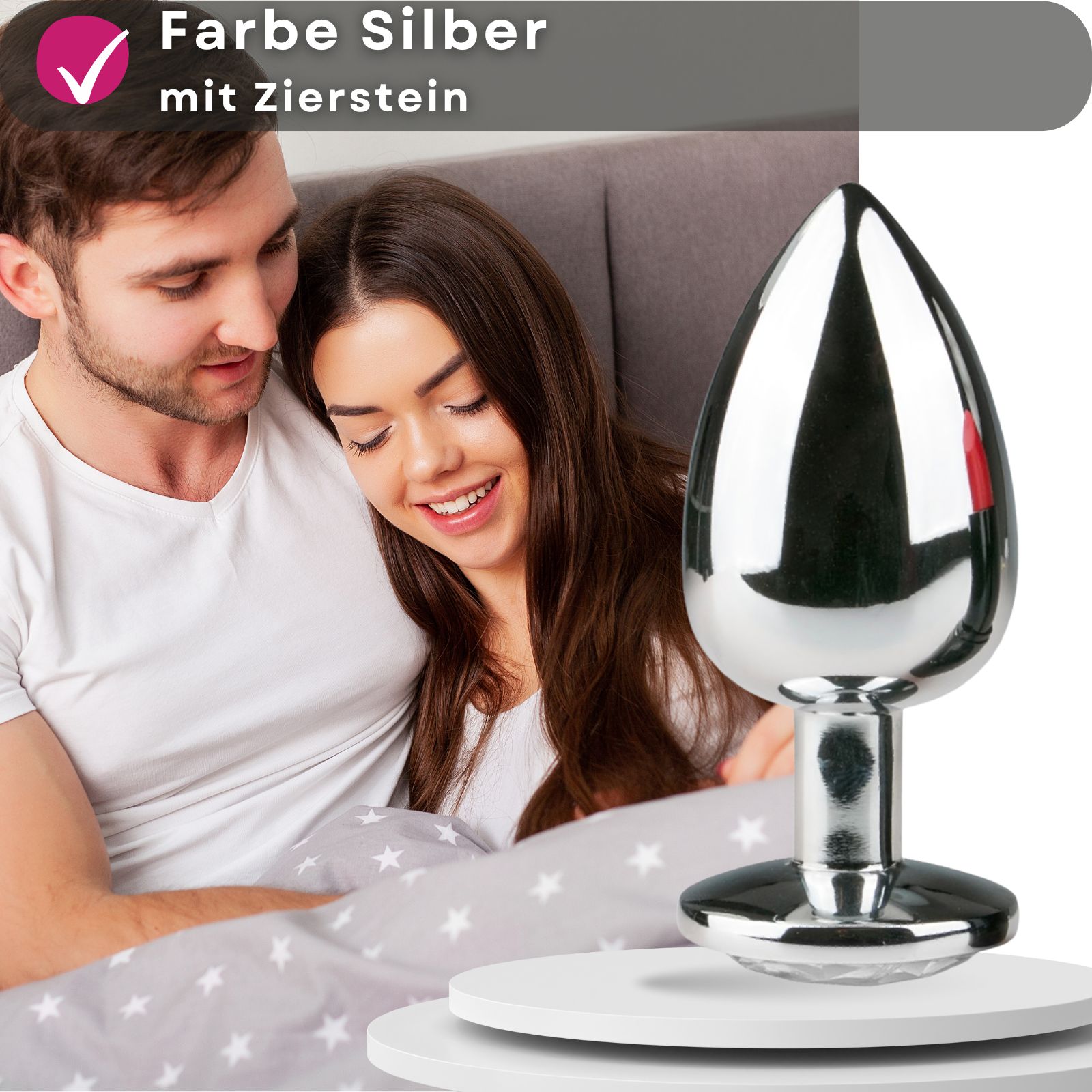 Paar im Bett. Analplug mit Zierstein. Text: Farbe Silber mit Zierstein.