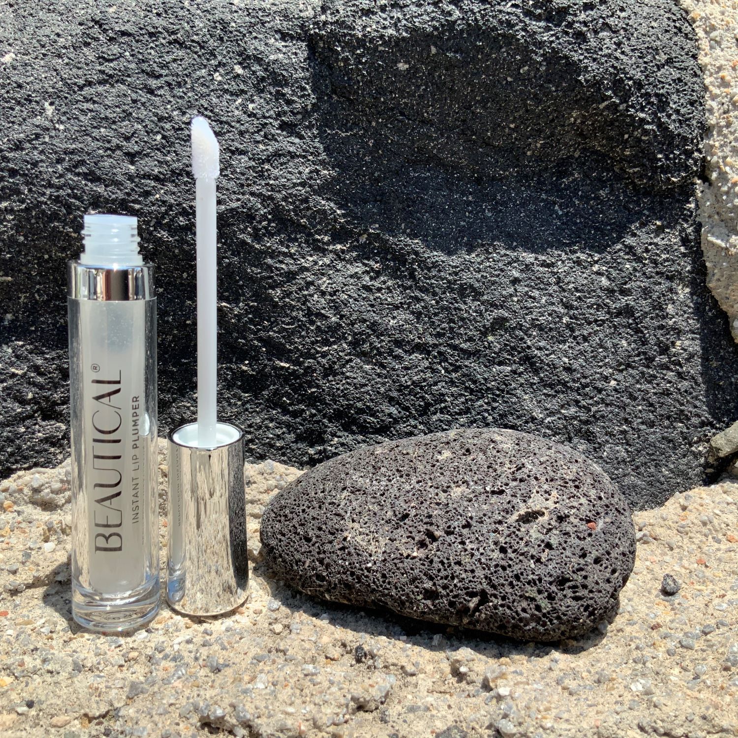 BEAUTICAL Instant Lip Plumper neben einem Stein. Der Applikator ist aus der Tube gezogen.