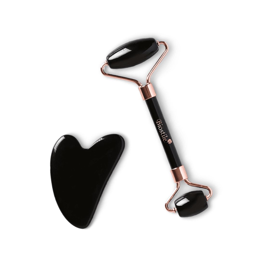 Schwarzer Gesichtsroller und Gua Sha. Goldfarbene Halterung am Roller. Beide aus glänzendem Material.