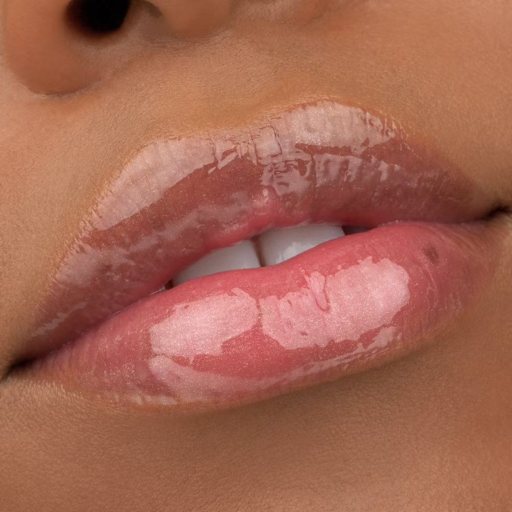 Nahaufnahme von Lippen mit glänzendem Lipgloss. Die Lippen sind rosa und glänzend.