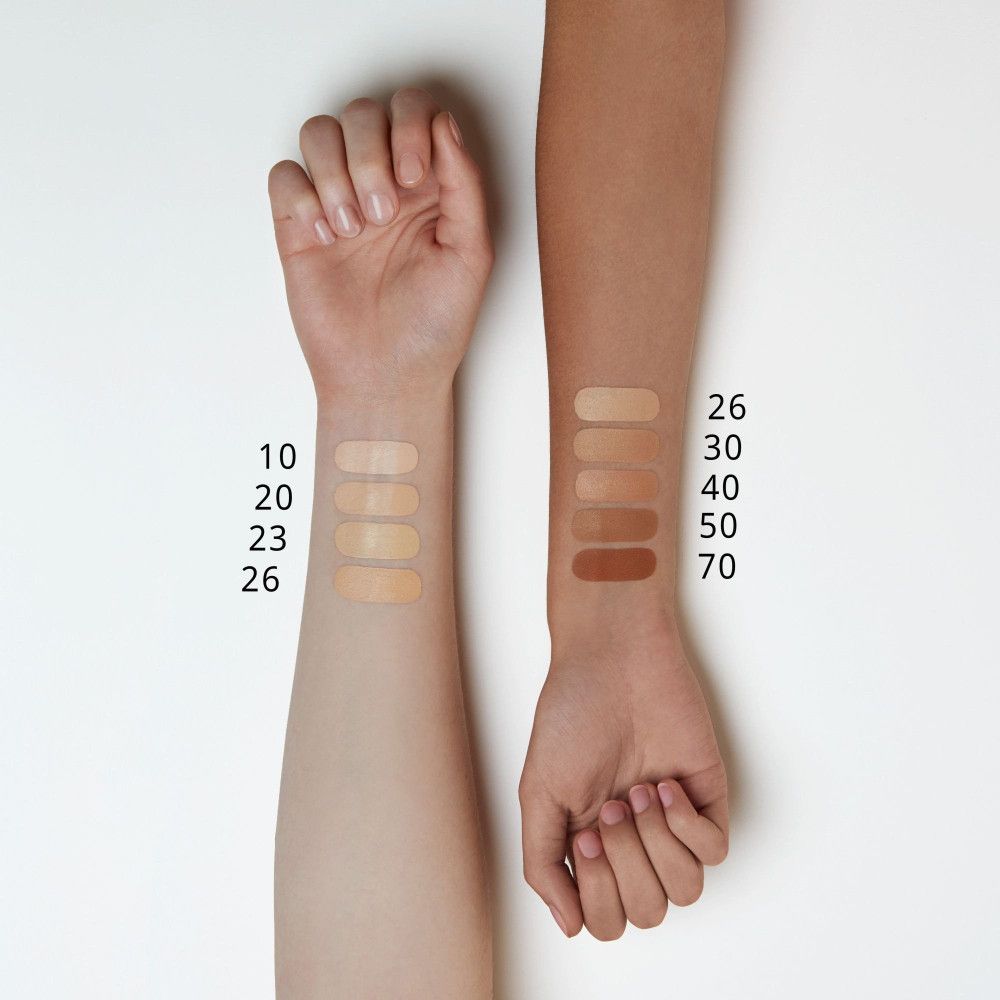 Arme mit Concealer-Farbmustern. Auf hellerer Haut: 10, 20, 23, 26. Auf dunklerer Haut: 26, 30, 40, 50, 70. Zahlen neben den Farbtönen.