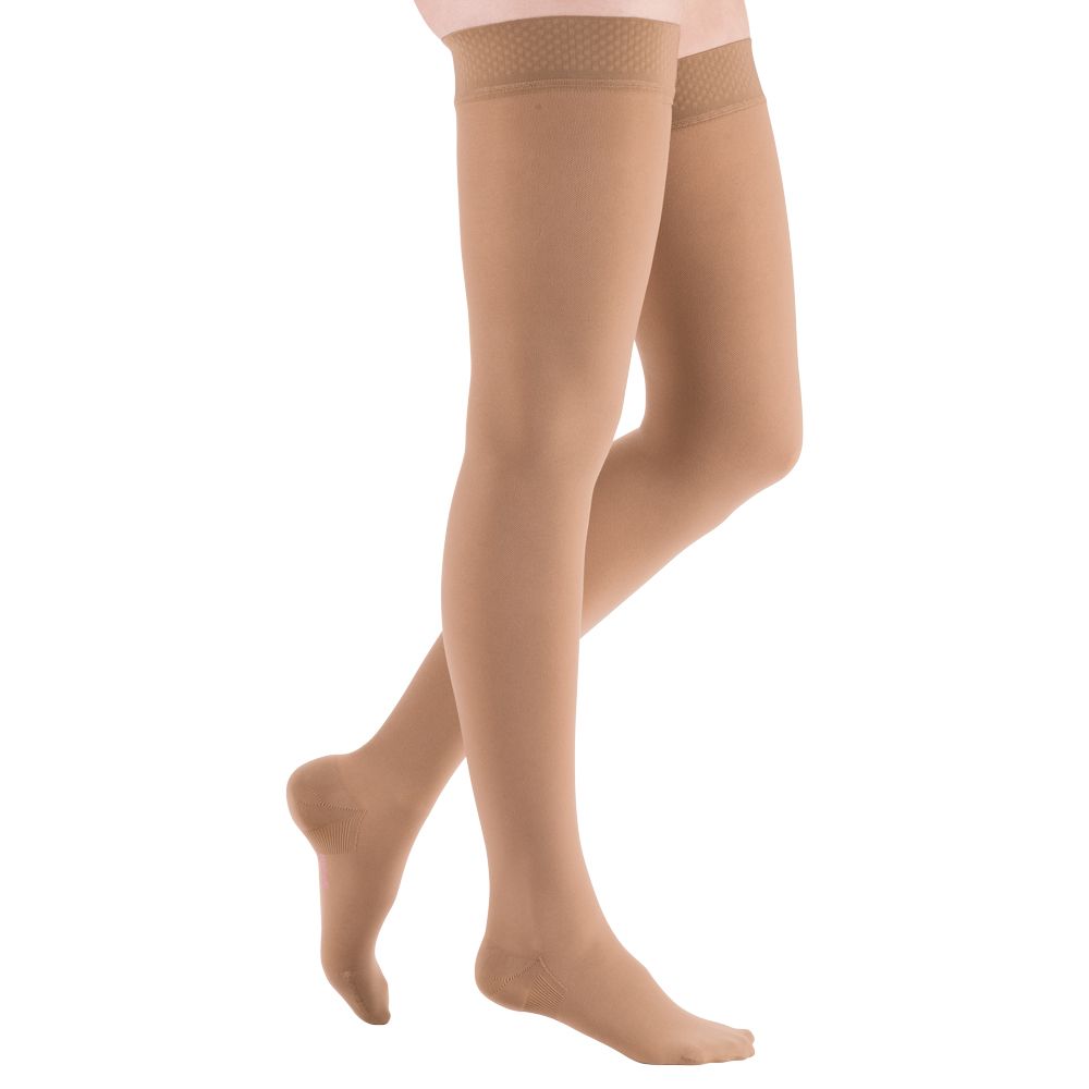 Beige Kompressionsstrümpfe mit Spitze am oberen Rand. Die Strümpfe bedecken die Beine bis zum Oberschenkel.