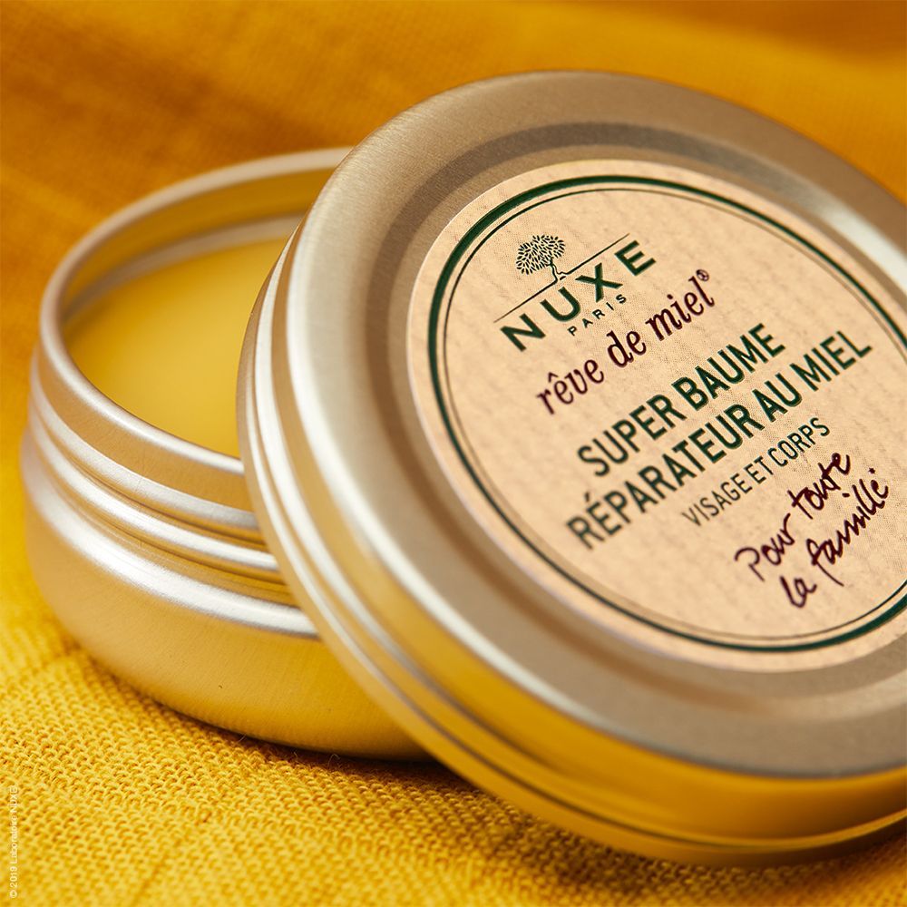 Runder Tiegel mit Deckel, geöffnet. Etikett mit Produktnamen und Logo. Gelbliche Creme sichtbar.