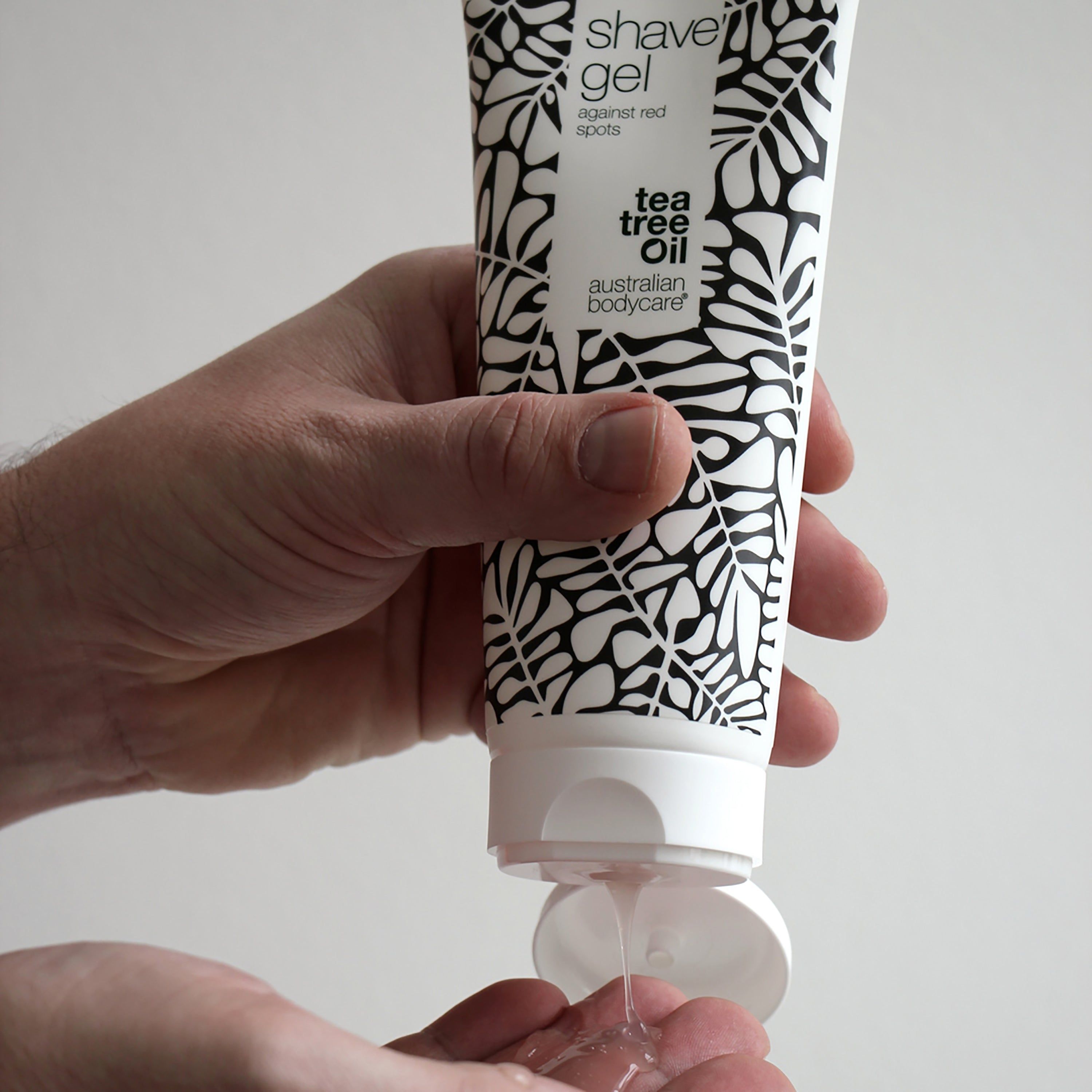 Person hält Tube Rasiergel. Gel wird in die Hand gedrückt. Aufschrift: shave gel against red spots. Australian Bodycare.