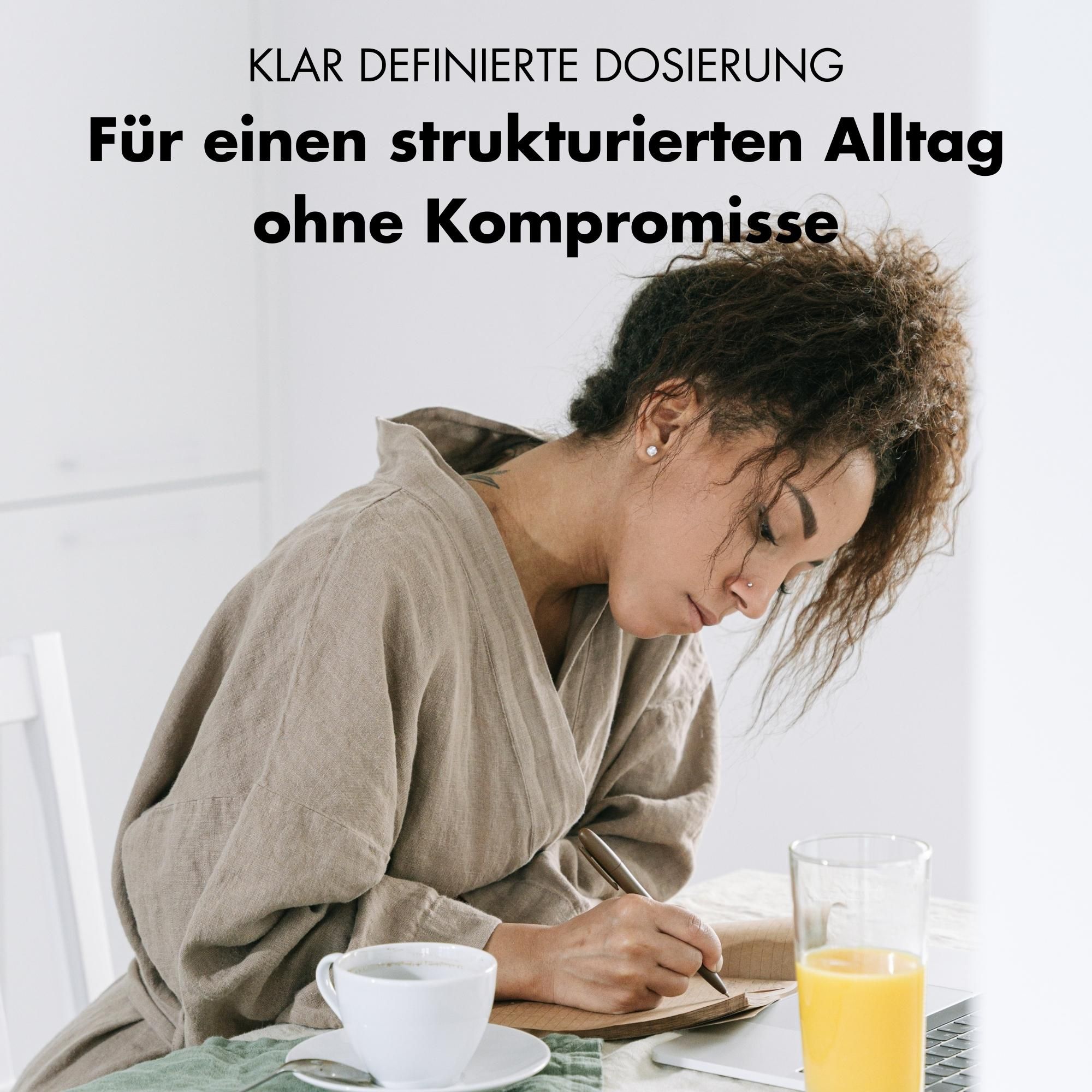 Frau schreibt am Tisch. Tasse Kaffee, Glas Orangensaft. Text: KLAR DEFINIERTE DOSIERUNG. Ohne Kompromisse.