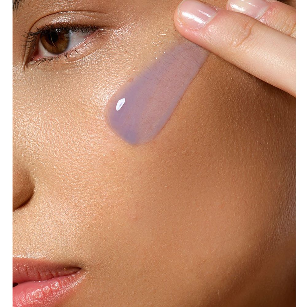 Person trägt Serum auf die Haut auf. Das Serum ist lila und transparent.