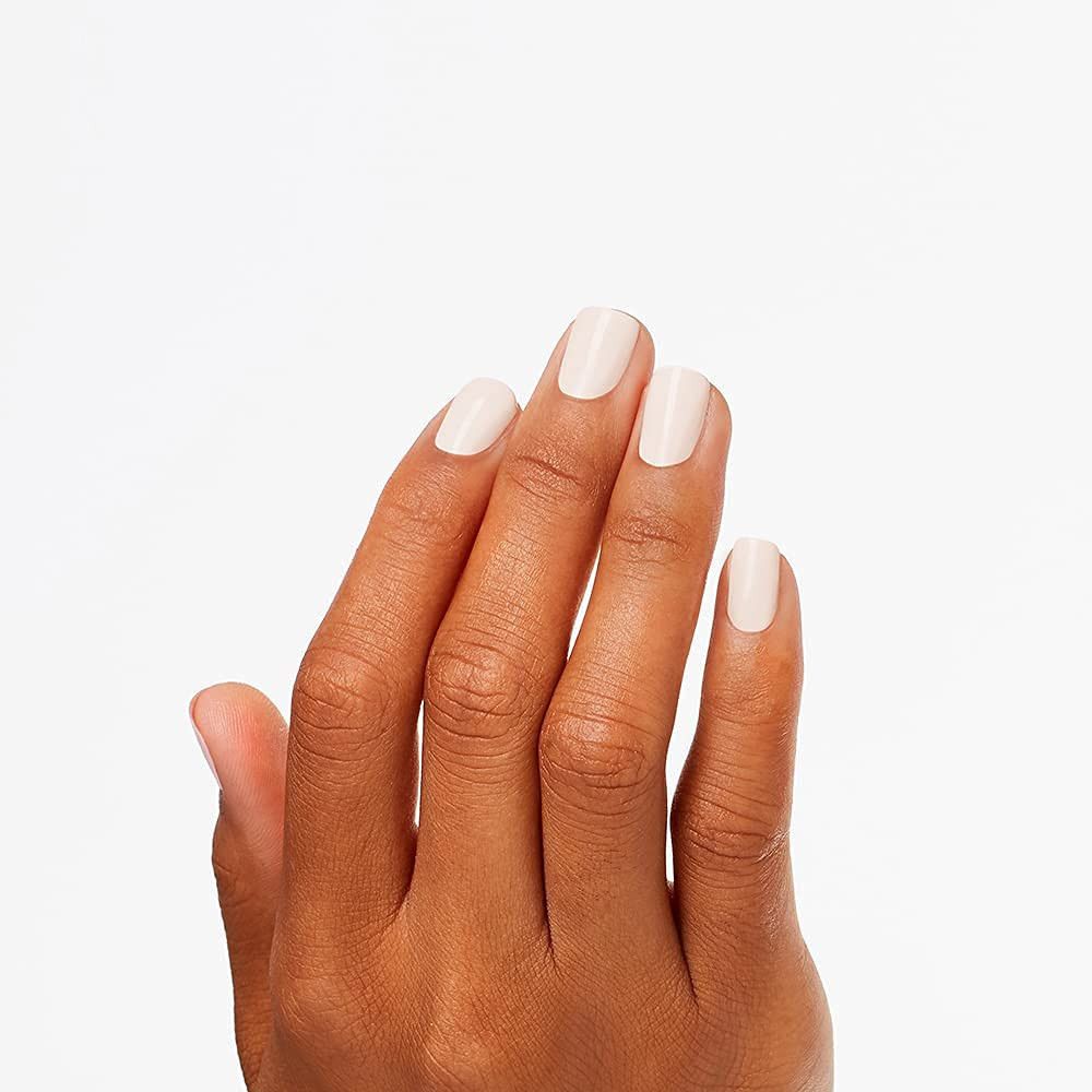 Hand mit lackierten Nägeln. Nägel sind hellbeige. Hintergrund ist weiß.