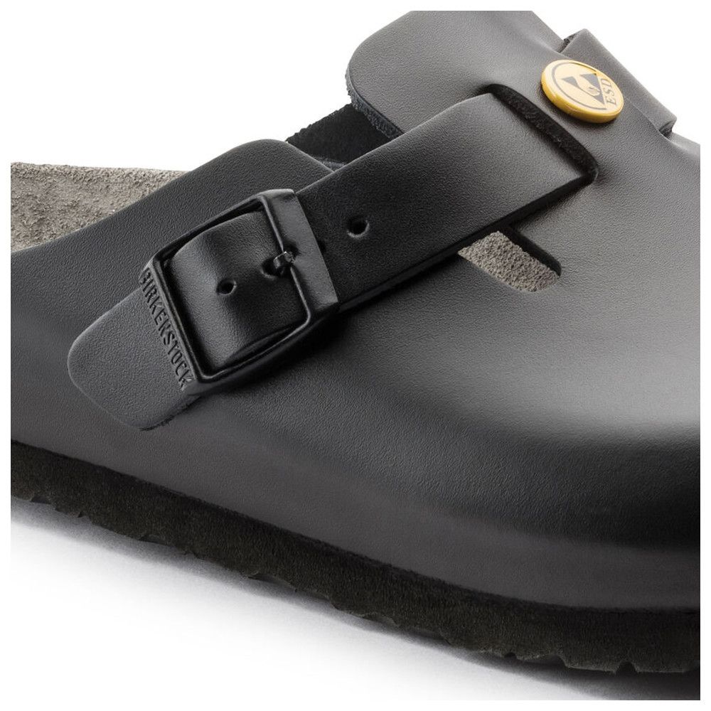Nahaufnahme einer schwarzen Pantolette mit Schnalle. Birkenstock-Logo auf der Schnalle. Gelbes Logo.