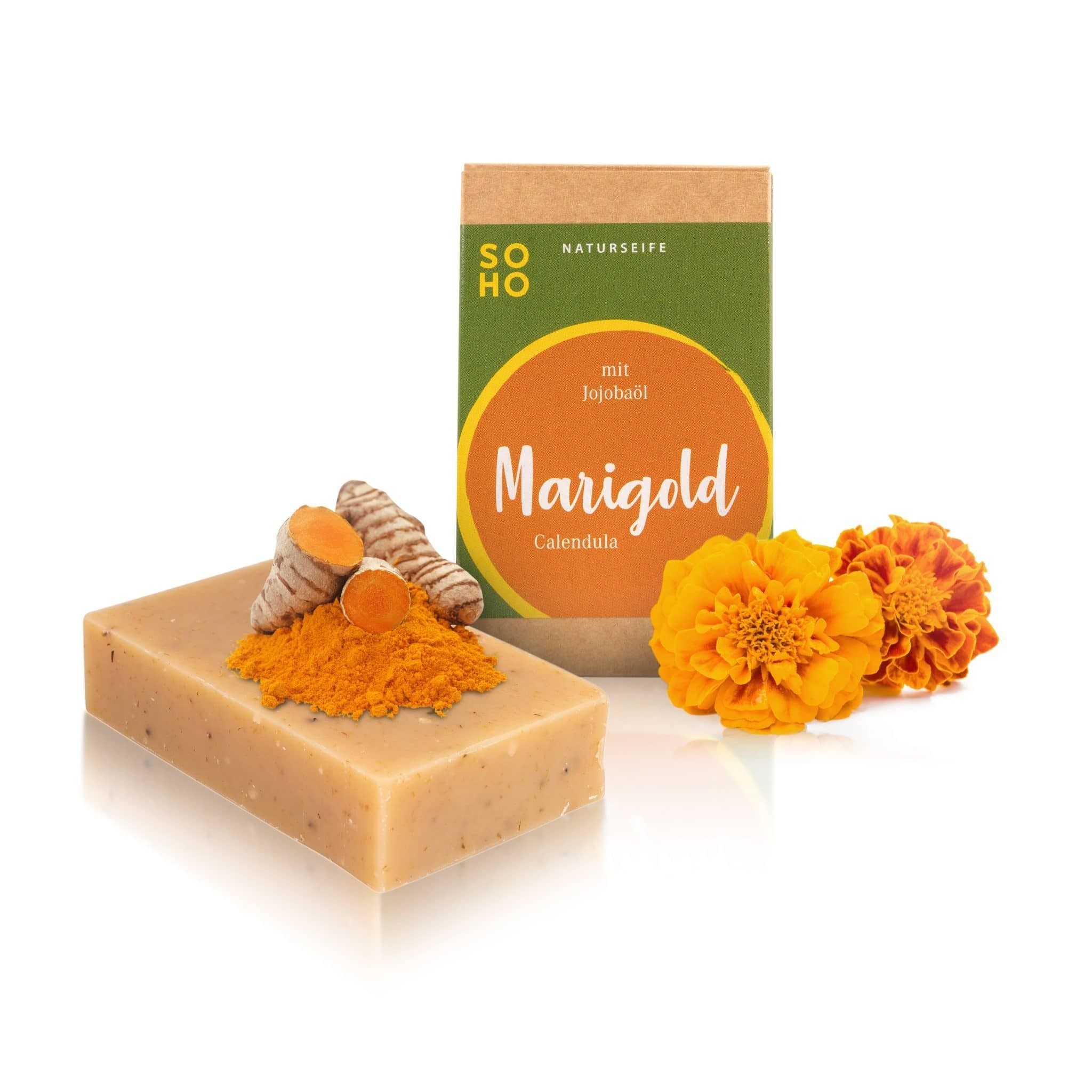 Seife mit Kurkuma, Ringelblumen und Verpackung. Verpackung mit "Marigold" Schriftzug. "SOHO Naturkosmetik" Logo.  "Mit Jojobaöl" Text.