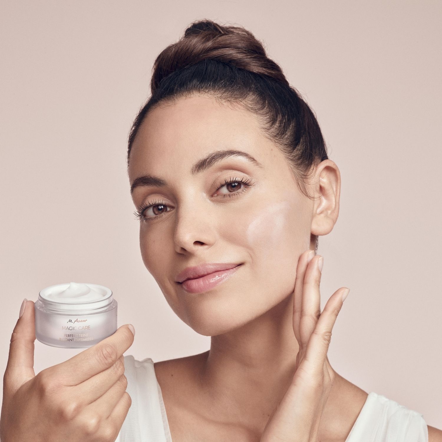 Frau hält Cremebehälter. Trägt Creme auf. Text: M. Asam MAGIC CARE PERFECT TEINT INSTANT OPTIMIZER.