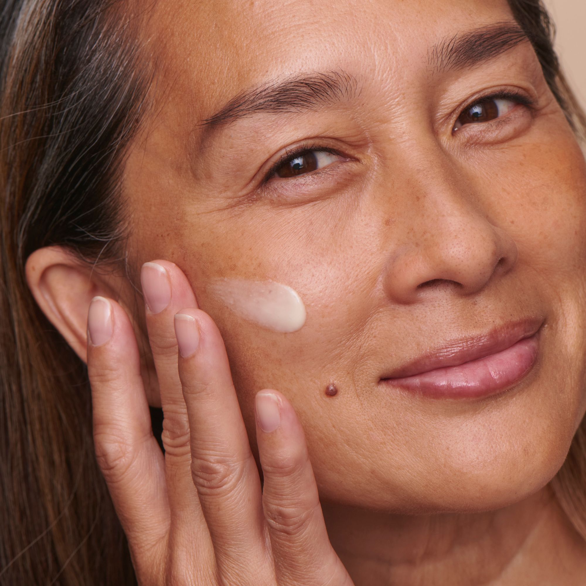 Frau trägt Serum auf. Creme auf der Haut. Gesicht nah.