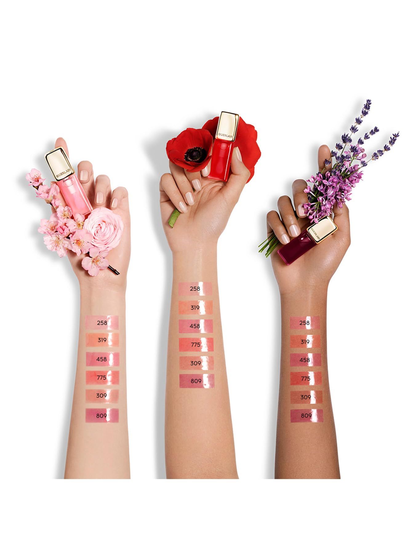 Drei Hände mit verschiedenen Lippenfarben. Auf den Armen Farbmuster. Lippenstifte mit goldenen Kappen. Blumenarrangements.