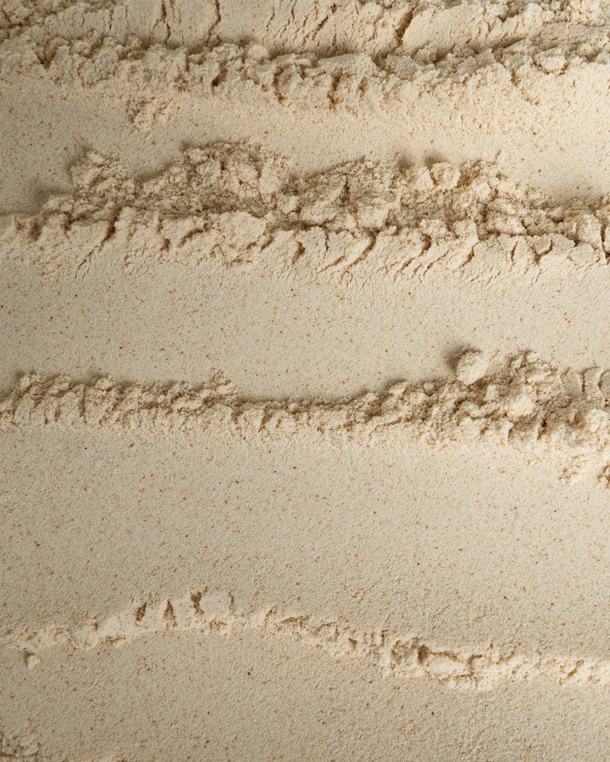 Nahaufnahme von buXtrade Nattokinase Pulver mit wellenförmigen Texturen.