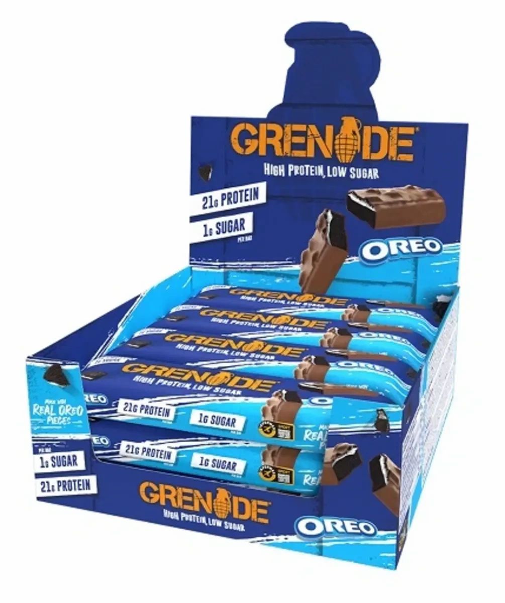 Verkaufsdisplay mit Proteinriegeln. Blaue Verpackung mit 'Grenade' und 'Oreo' Schriftzug. Enthält 21g Protein und 1g Zucker.