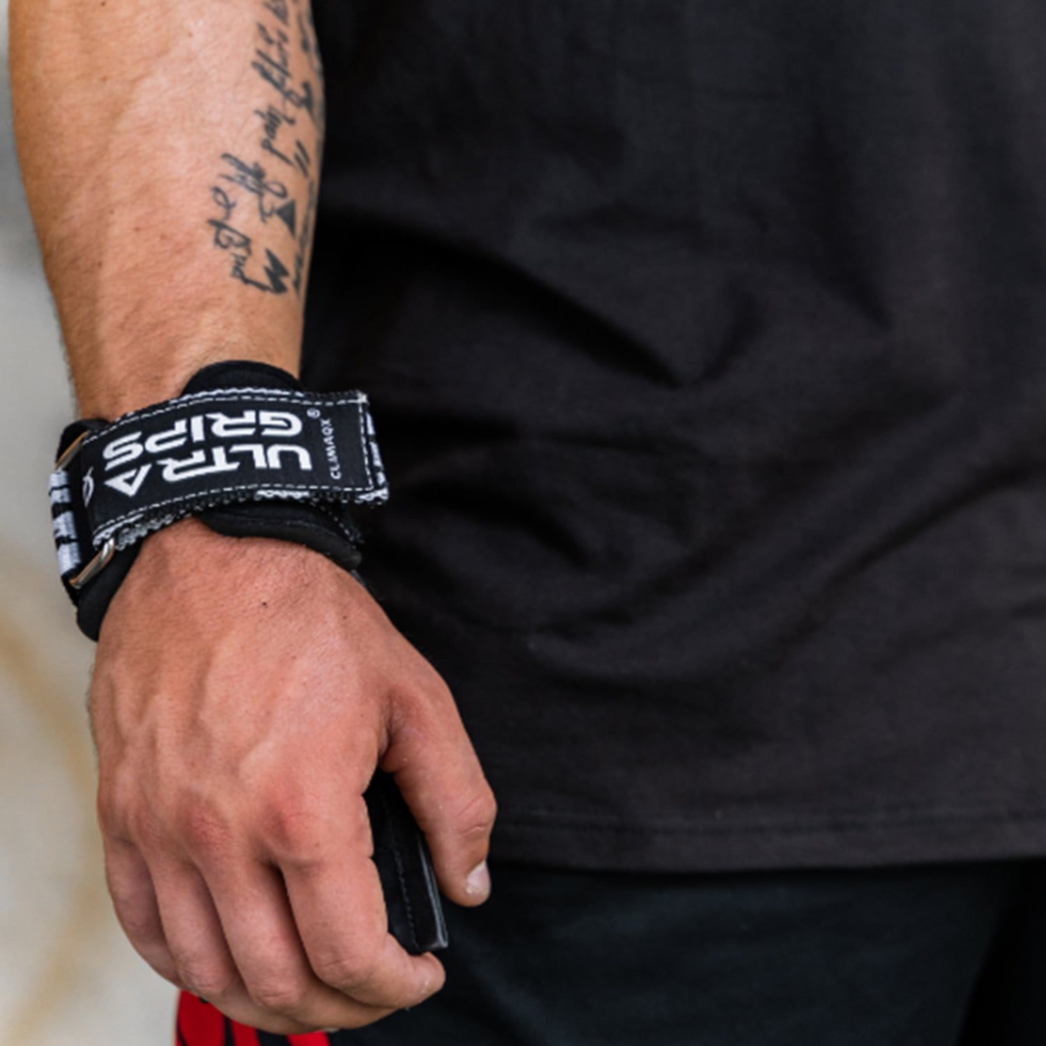 Handgelenkbandage mit Aufschrift ULTRA GRIPS. Schwarzes Band mit weißer Schrift. Metallring.