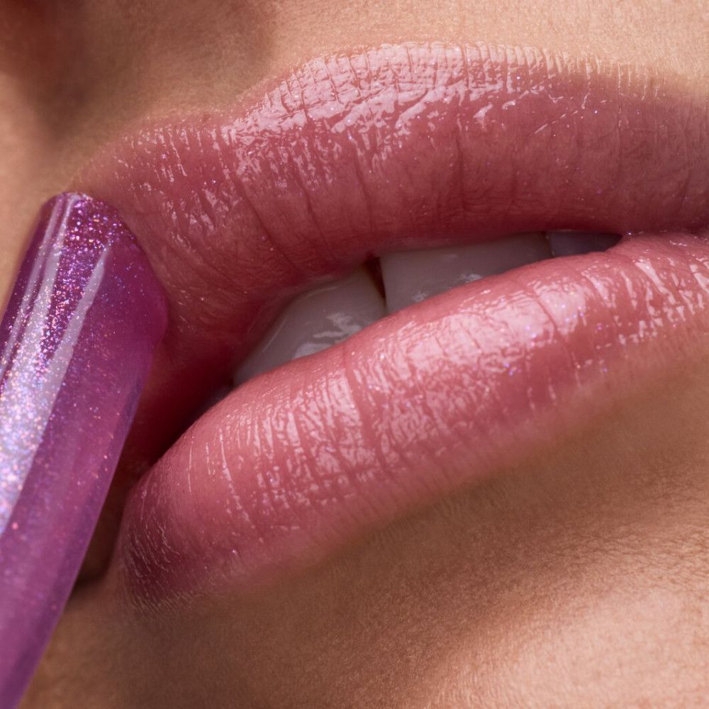 Nahaufnahme von Lippen, die mit rosa Lippenbalsam bedeckt sind. Ein Stift ist sichtbar.
