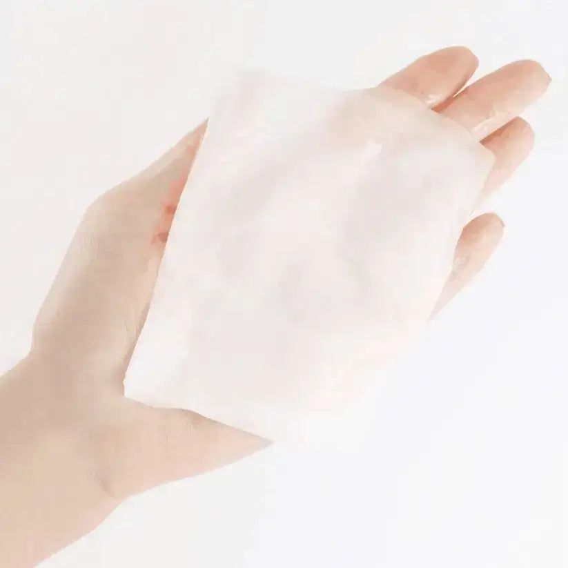Feuchtigkeitsspendende Tuchmaske in Hand gehalten. Rechteckige Form, weiß, leicht transparent.