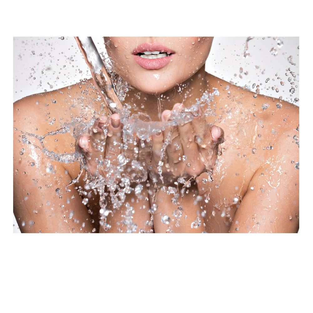 Nahaufnahme einer Person, die Wasser in ihren Händen auffängt. Wasser spritzt. Nur Hals und Gesicht sichtbar.