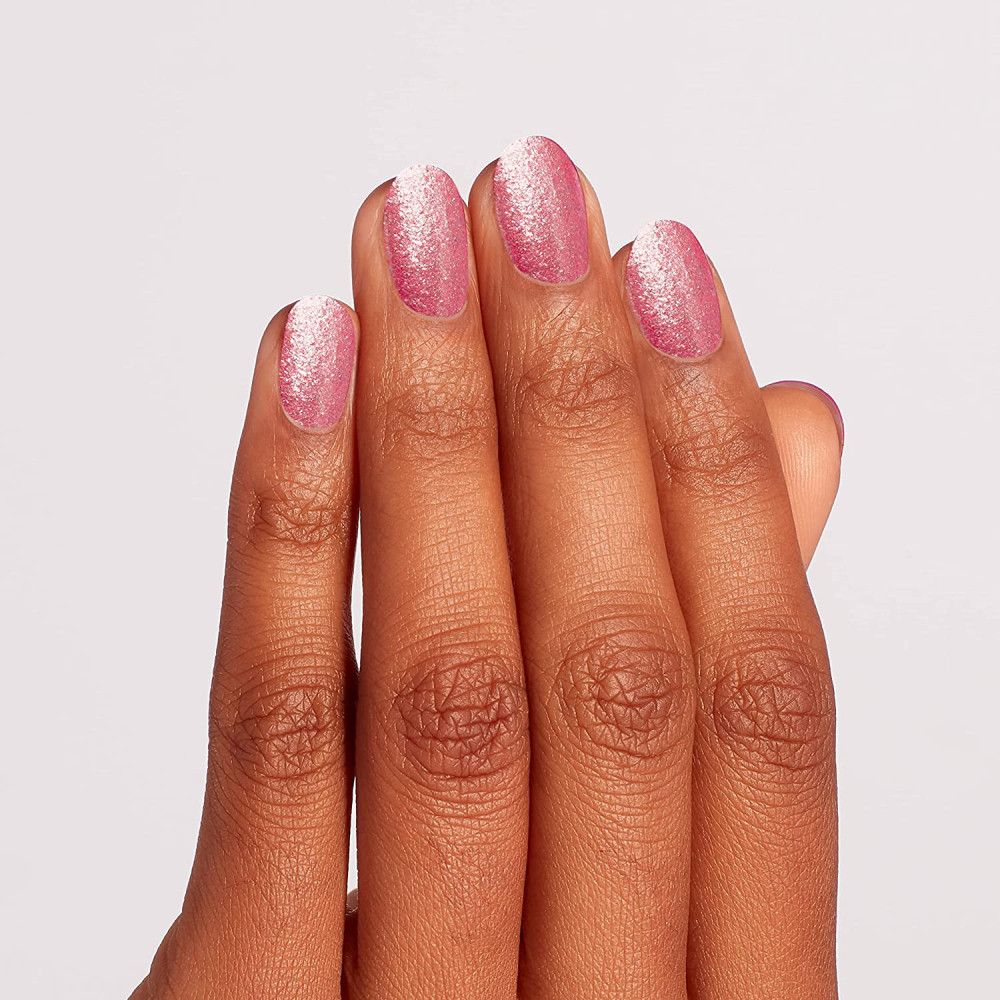 Hand mit lackierten Nägeln. Rosa Nagellack mit Glitzer.