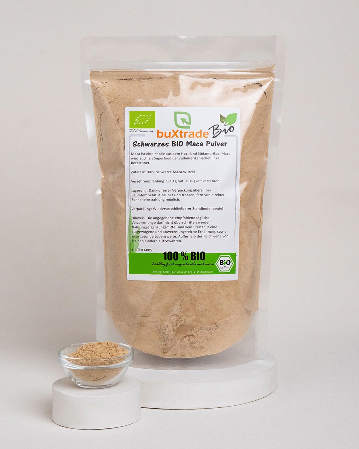 Verpackung mit schwarzem Bio Maca Pulver, daneben eine Schale mit Pulver.