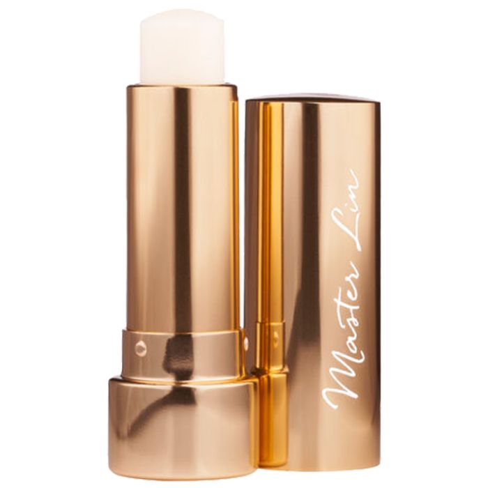 Goldfarbener Lippenbalsam in Stiftform. Der Deckel ist geöffnet und zeigt den Lippenbalsam. Auf dem Deckel steht "Master Lin".