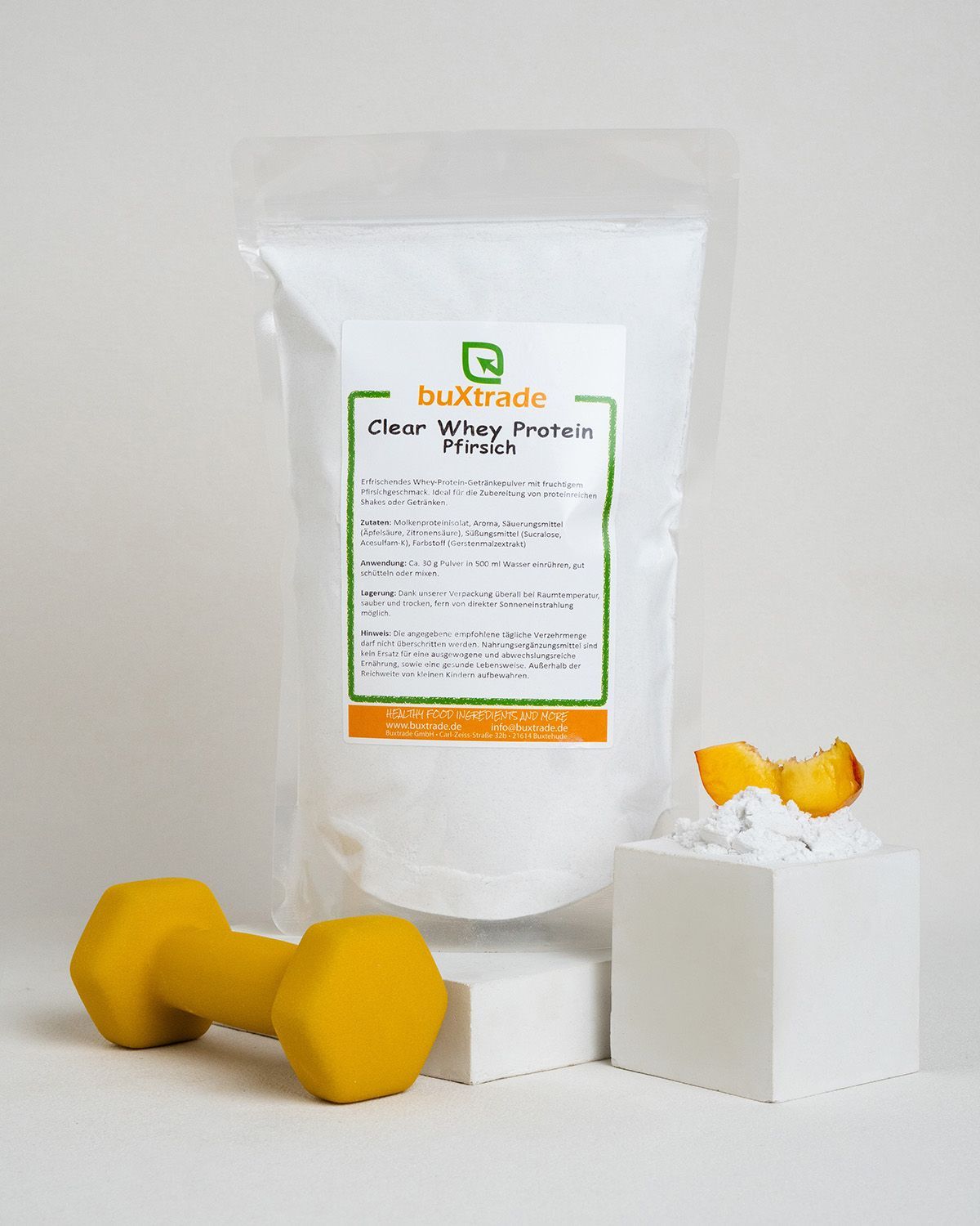 Ein Beutel buxtrade Clear Whey Protein Pfirsich mit einem gelben Hantel und Pfirsichstücken auf einem Würfel.