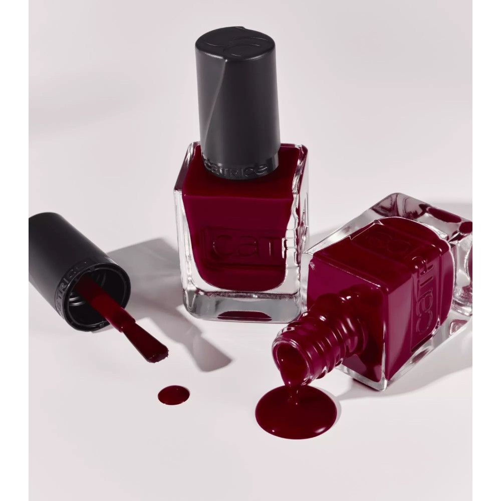 Drei Nagellackflaschen. Roter Nagellack. Schwarze Deckel. Eine Flasche liegt. Nagellack verschüttet.