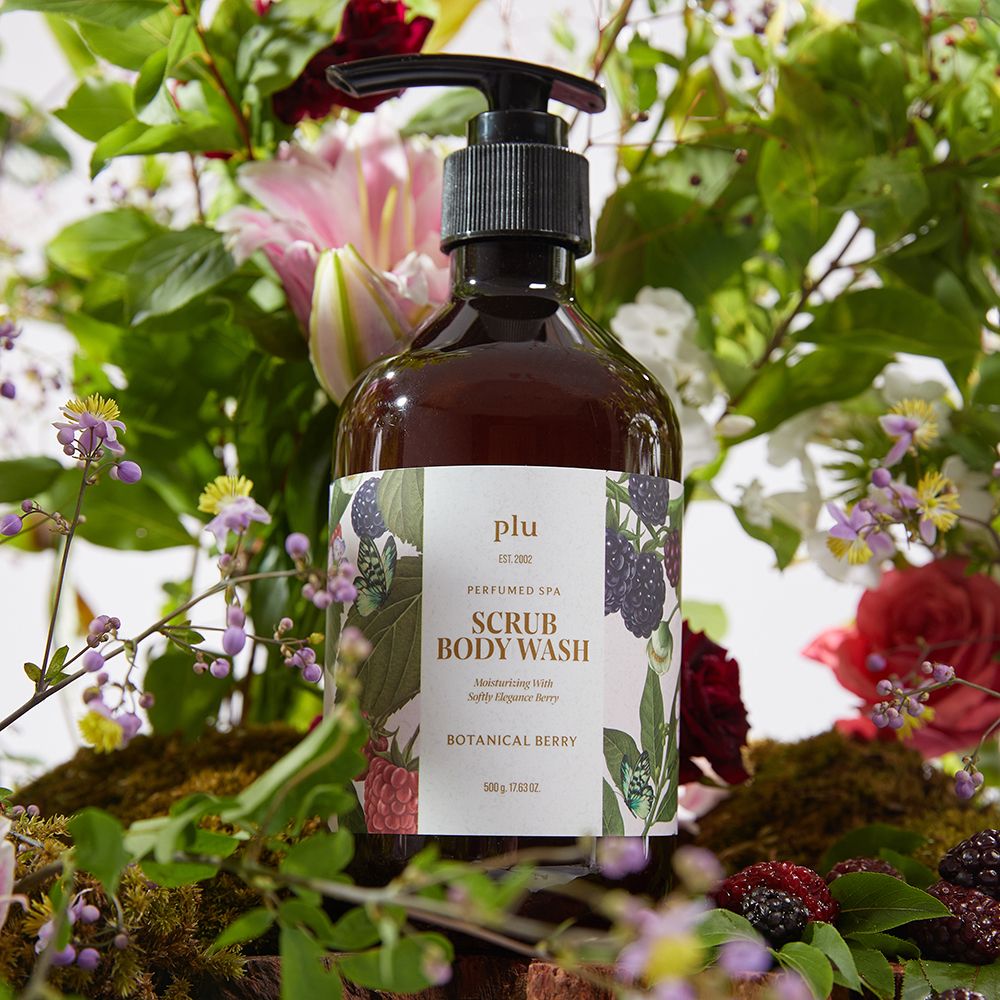 Duschgel-Flasche mit Pumpe, umgeben von Blumen. Etikett mit Produktnamen und botanischen Illustrationen. Schwarze Pumpe. Produktname: Scrub Body Wash Botanical Berry.