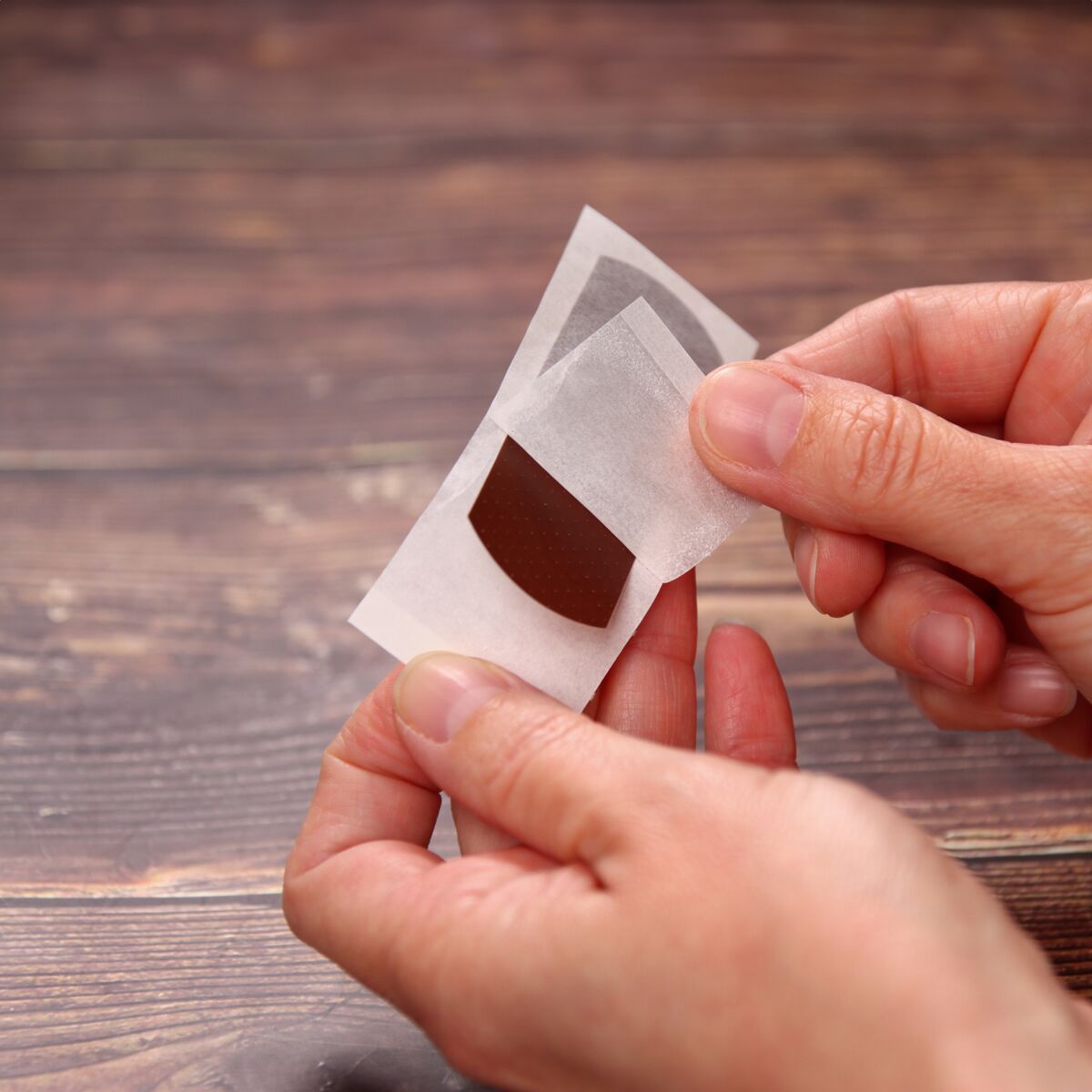 Hände entfernen braunen WERO Weroplast SkinColor Pflasterstreifen von der Schutzfolie.