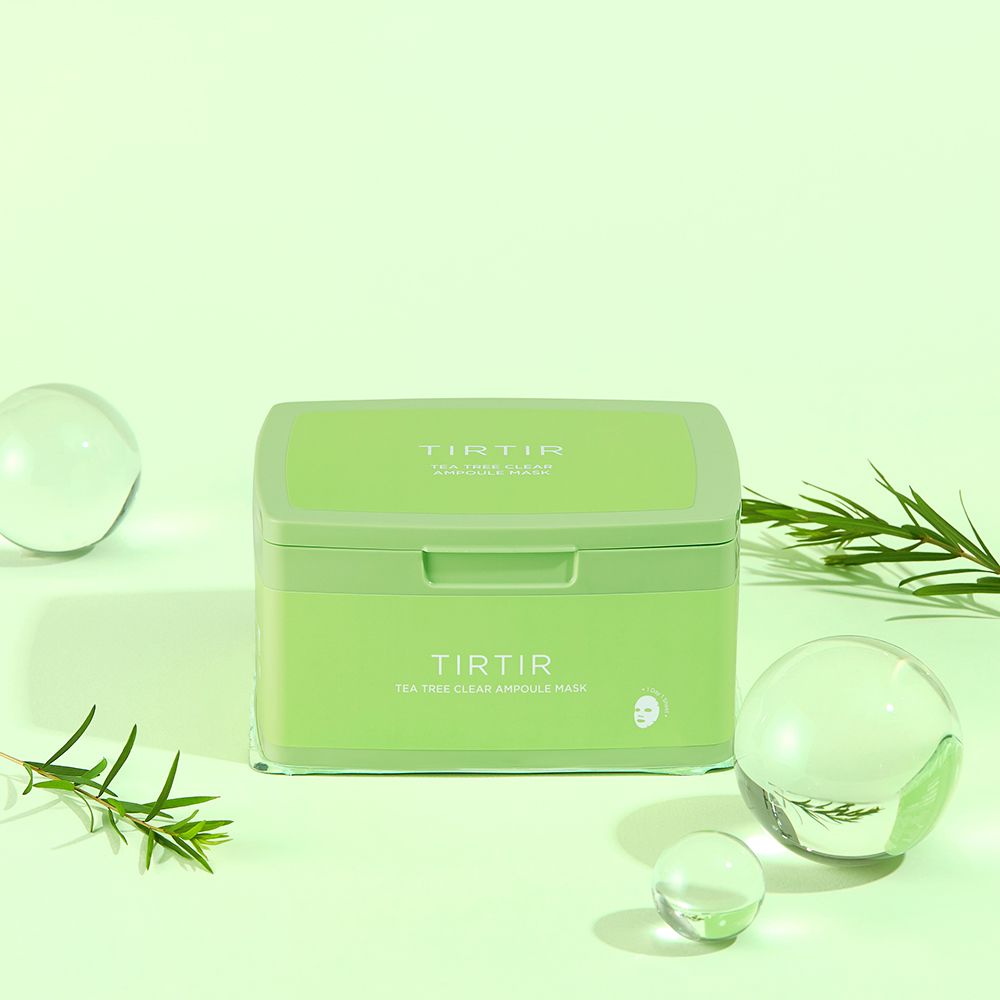 Grüne Box mit Aufschrift TIR TIR Tea Tree Clear Ampoule Mask. Dekorative Elemente: Glaskugeln und Zweige.