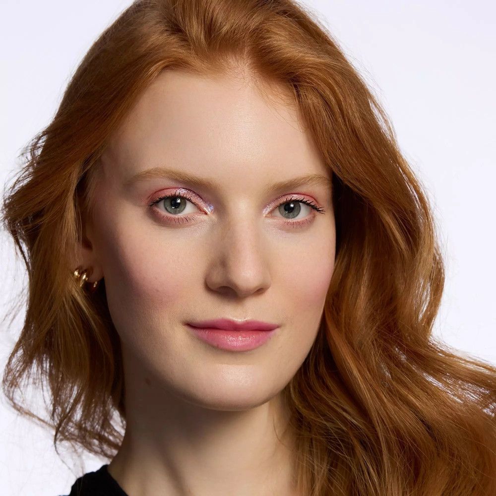 Porträt einer Frau mit rosa Lidschatten. Rotes Haar. Goldene Ohrringe.