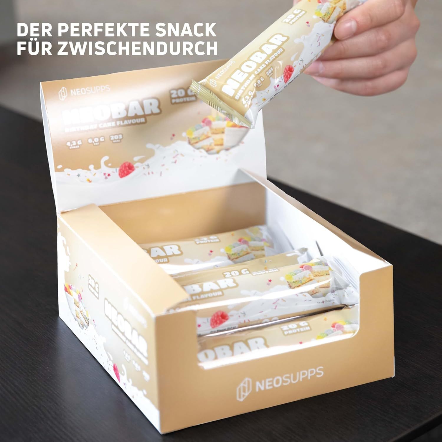 Eine Hand nimmt einen NeoBar-Riegel aus einer geöffneten Box. Auf dem Riegel steht "NeoBar".