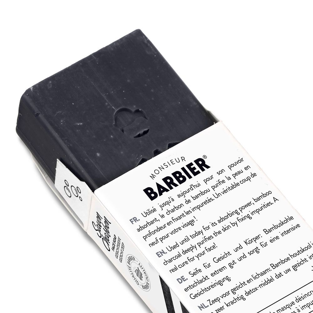 Schwarze Seife in geöffneter Verpackung. Text: "Monsieur BARBIER", "Savon Charbon".