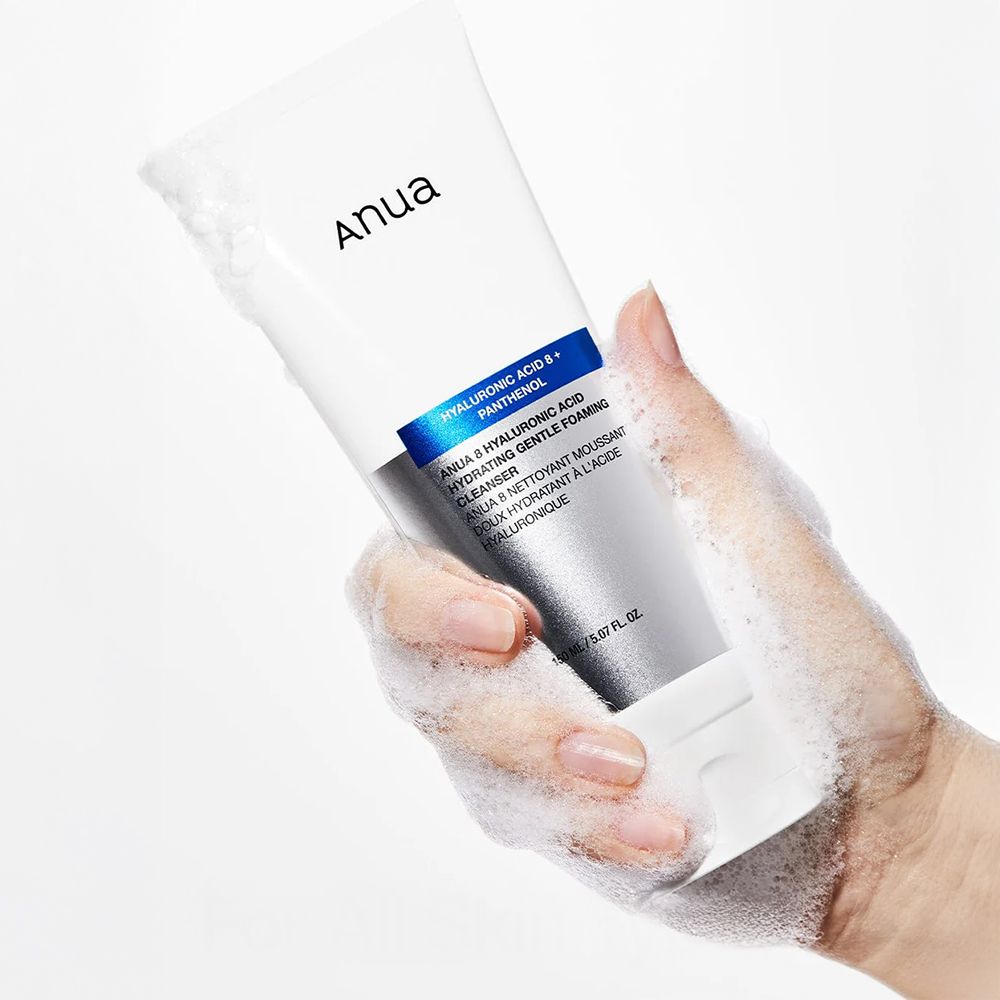 Hand hält ANUA Tube, umgeben von reinigendem Schaum.