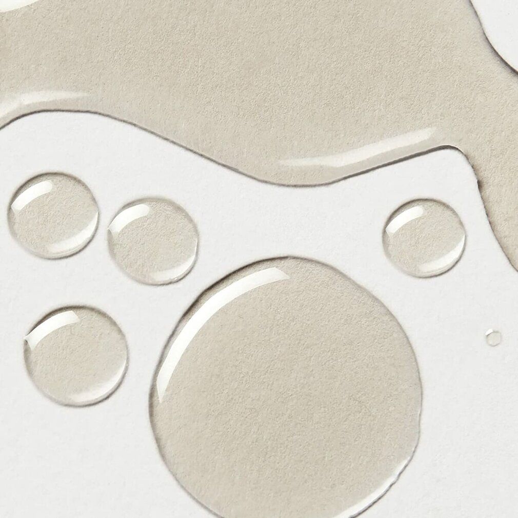 Nahaufnahme von transparenten Flüssigkeitstropfen auf weißem Untergrund. Verschiedene Größen und Formen.