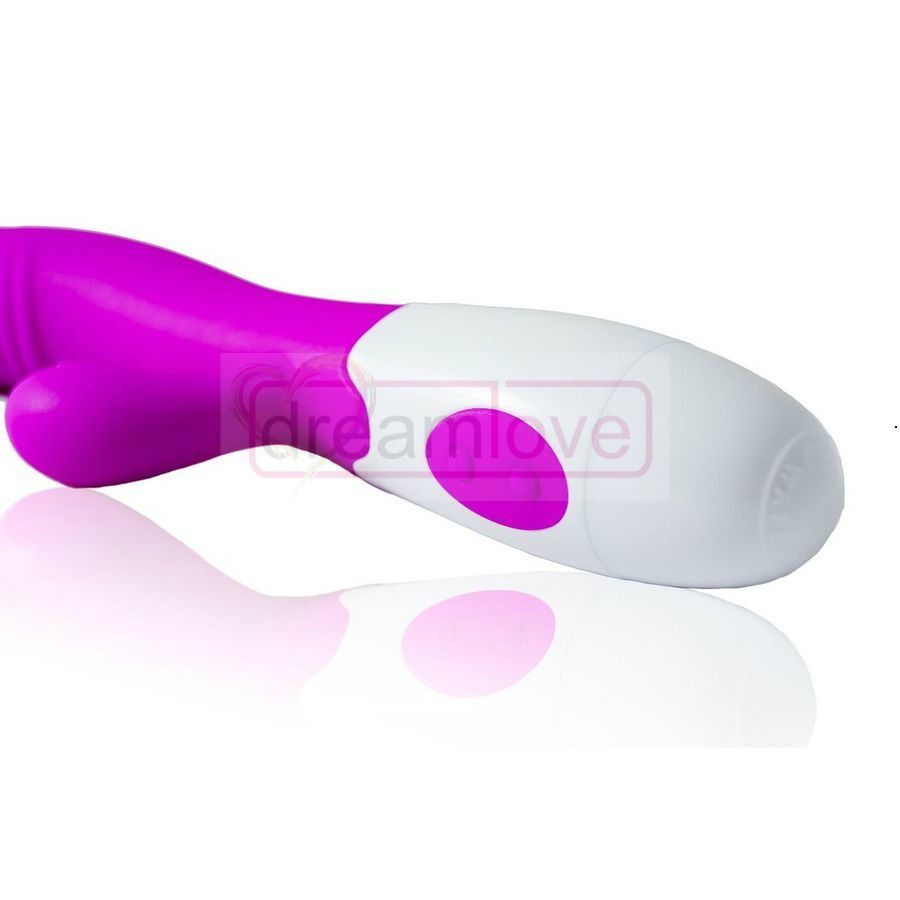 Nahaufnahme eines lila-weißen Vibrators. Der weiße Griff hat einen Knopf. Reflektion auf einer glatten Oberfläche.
