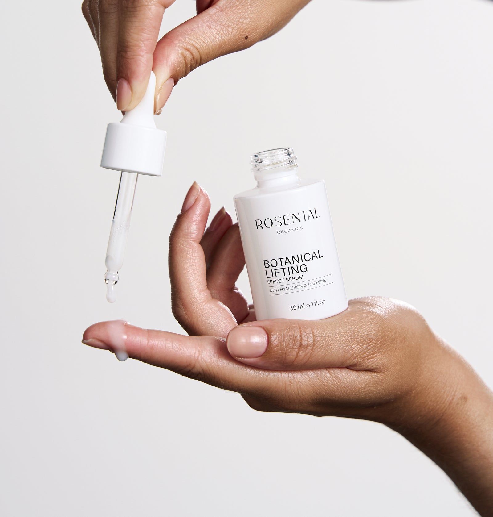 Weiße Serumflasche mit Pipette. Hände halten Flasche und Pipette. Tropfen Serum auf Hand. Aufschrift: ROSENTAL ORGANICS, BOTANICAL LIFTING.
