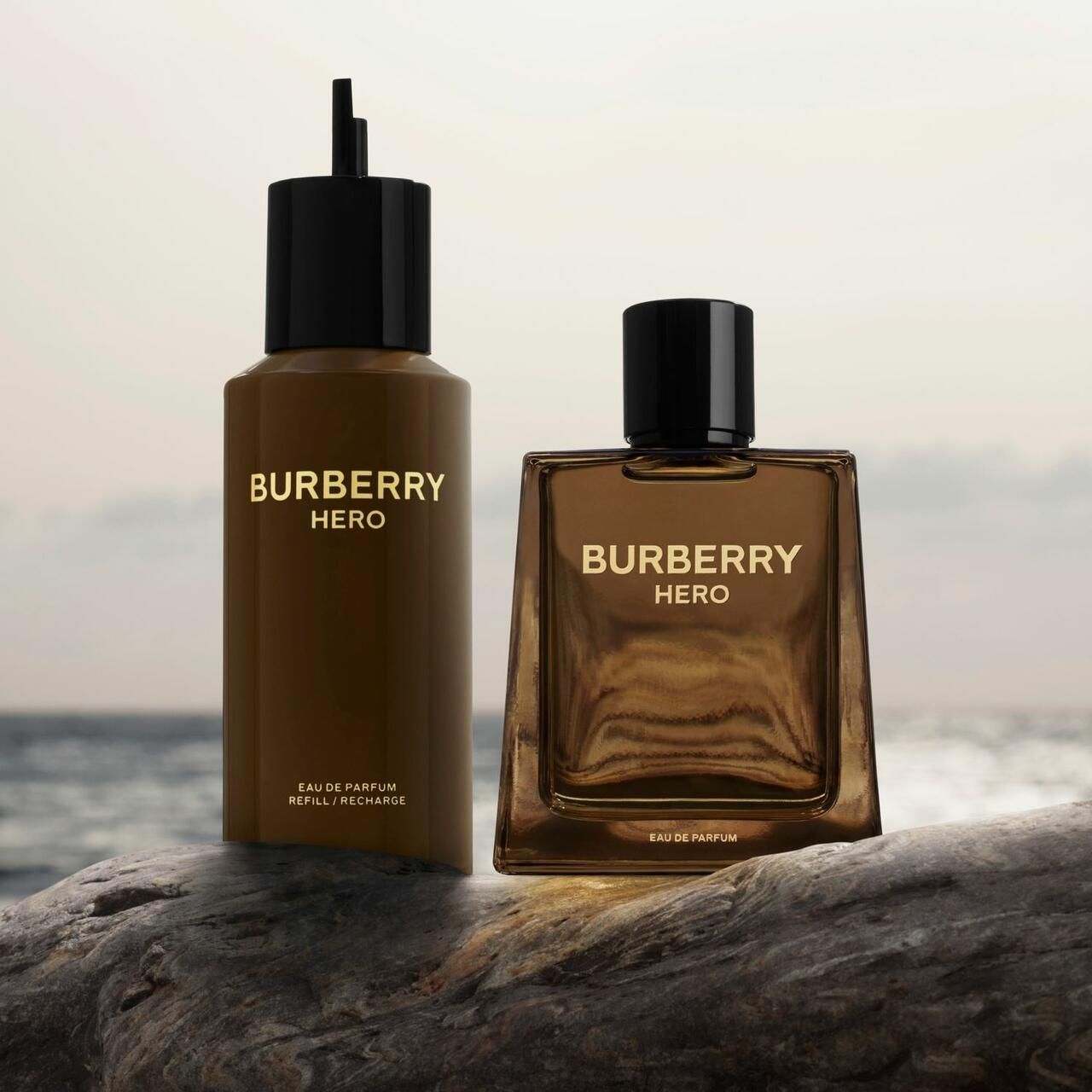 Zwei Burberry Hero Parfumflaschen. Links: Nachfüllflasche. Rechts: Flakon. Beide braun mit schwarzem Deckel. Aufschrift: Burberry Hero.