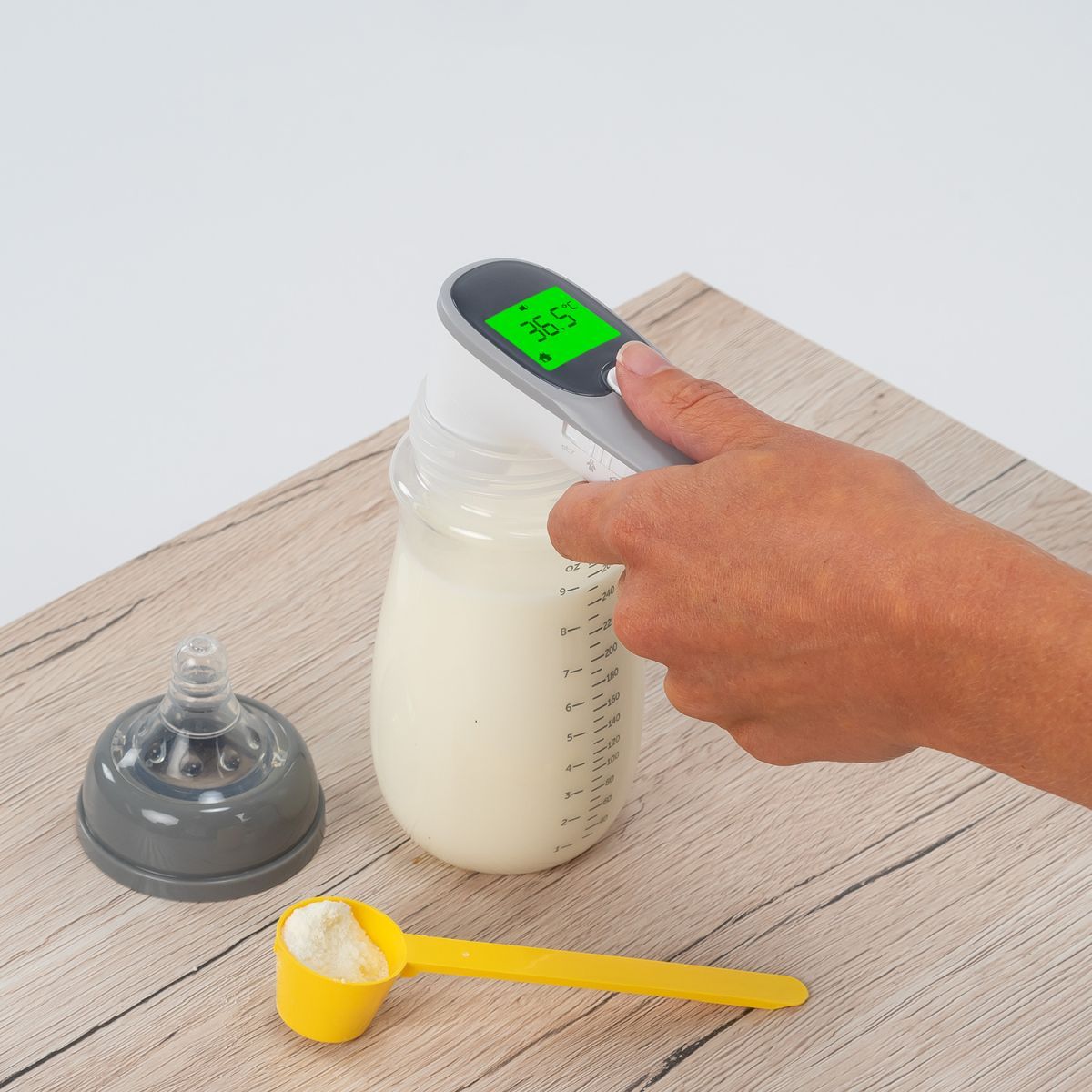 Infrarot-Thermometer misst die Temperatur einer Flasche. Das Display zeigt 36,5°C an.