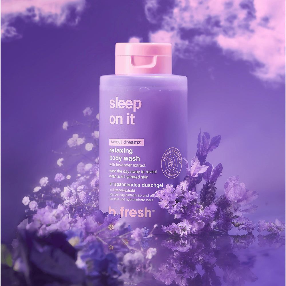 Lila Duschgel-Flasche mit rosa Deckel, umgeben von lila Blumen. Aufschrift: Sleep On It, Relaxing Body Wash, b.fresh. Vegan-Siegel.