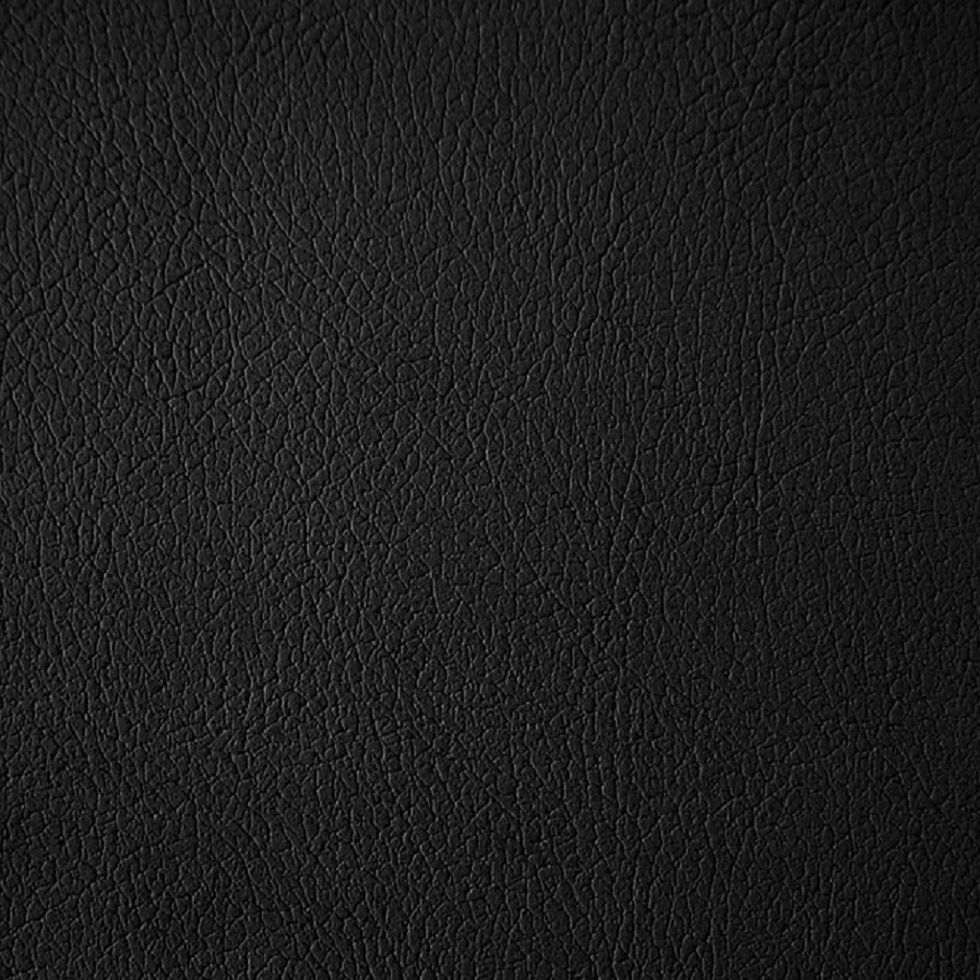 Nahaufnahme einer schwarzen, lederartigen Oberfläche. Textur mit feinen Falten und Unebenheiten.