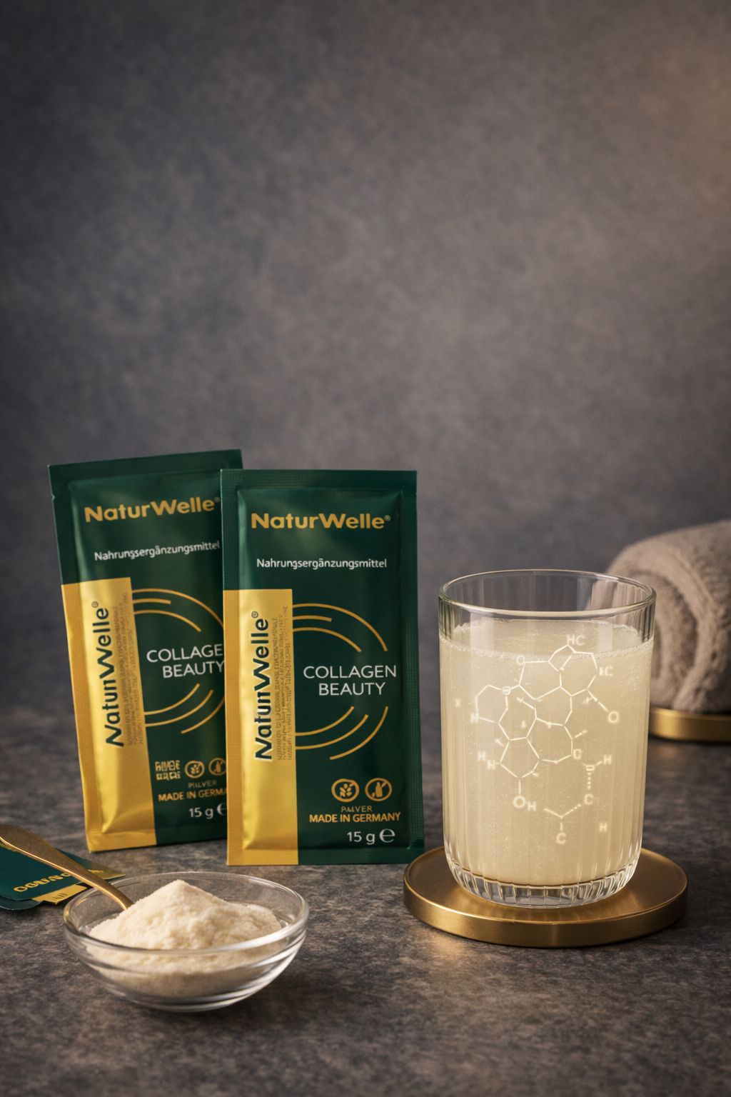 Zwei Beutel Kollagen Beauty neben Glas mit Flüssigkeit. Schale mit Pulver. Goldener Untersetzer.