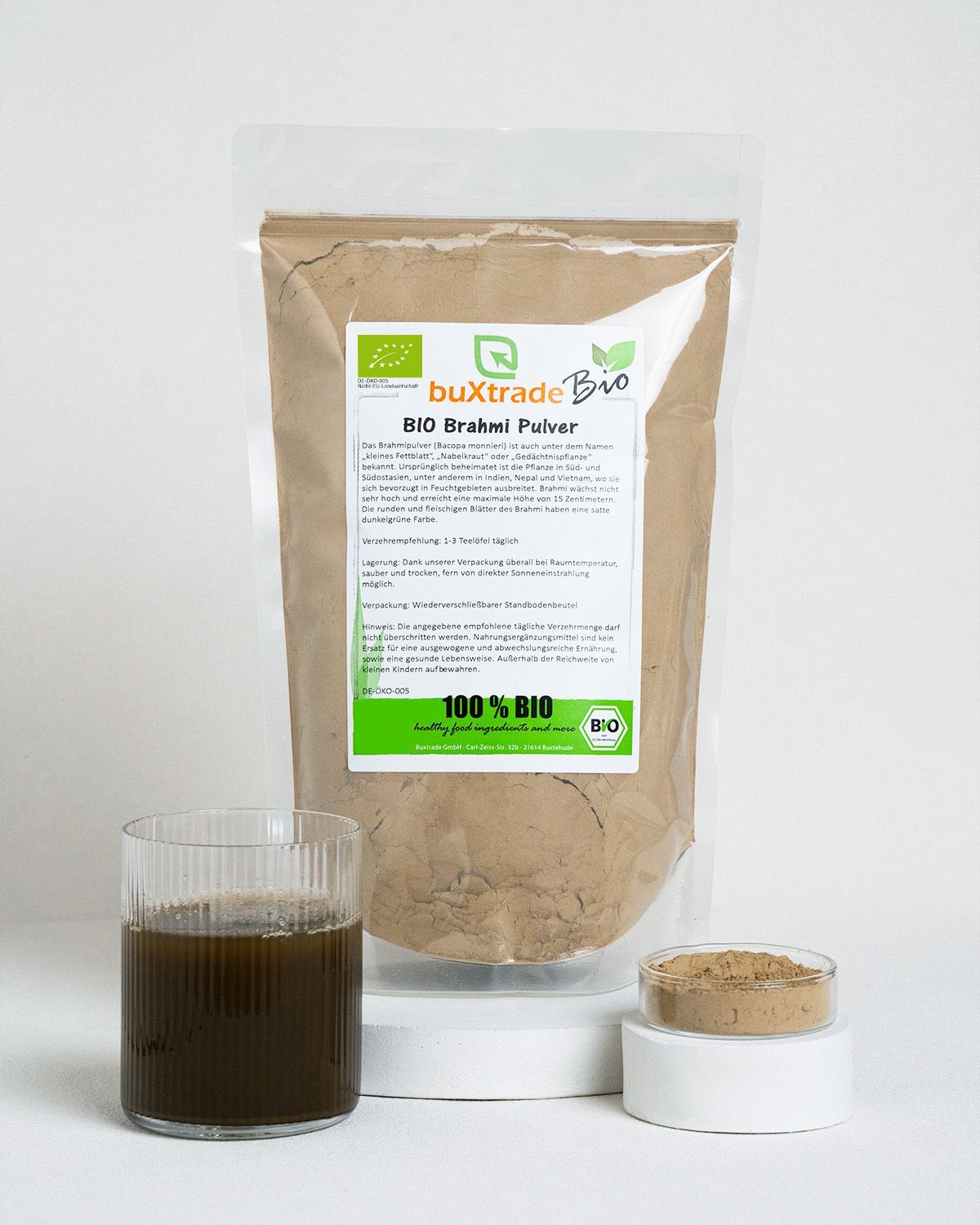 Verpackung von Bio Brahmi Pulver neben einem Glas und einer Schale.