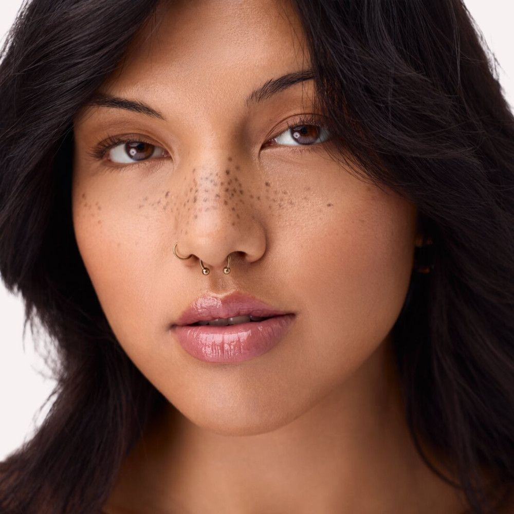 Porträt einer Frau mit aufgetragenem Lipgloss. Die Lippen sind glänzend und rosa.